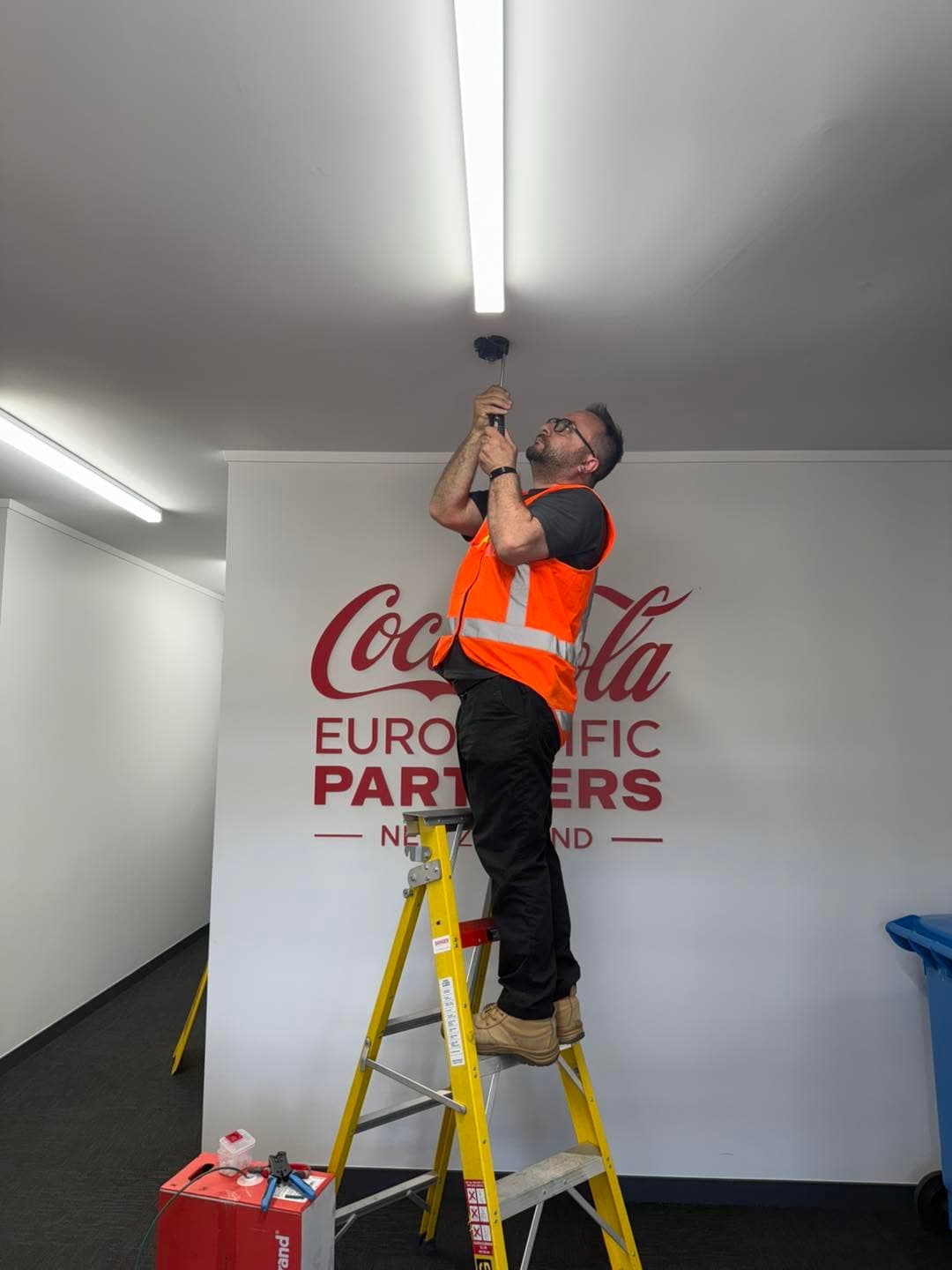 Technician installing a ceiling-mounted security device