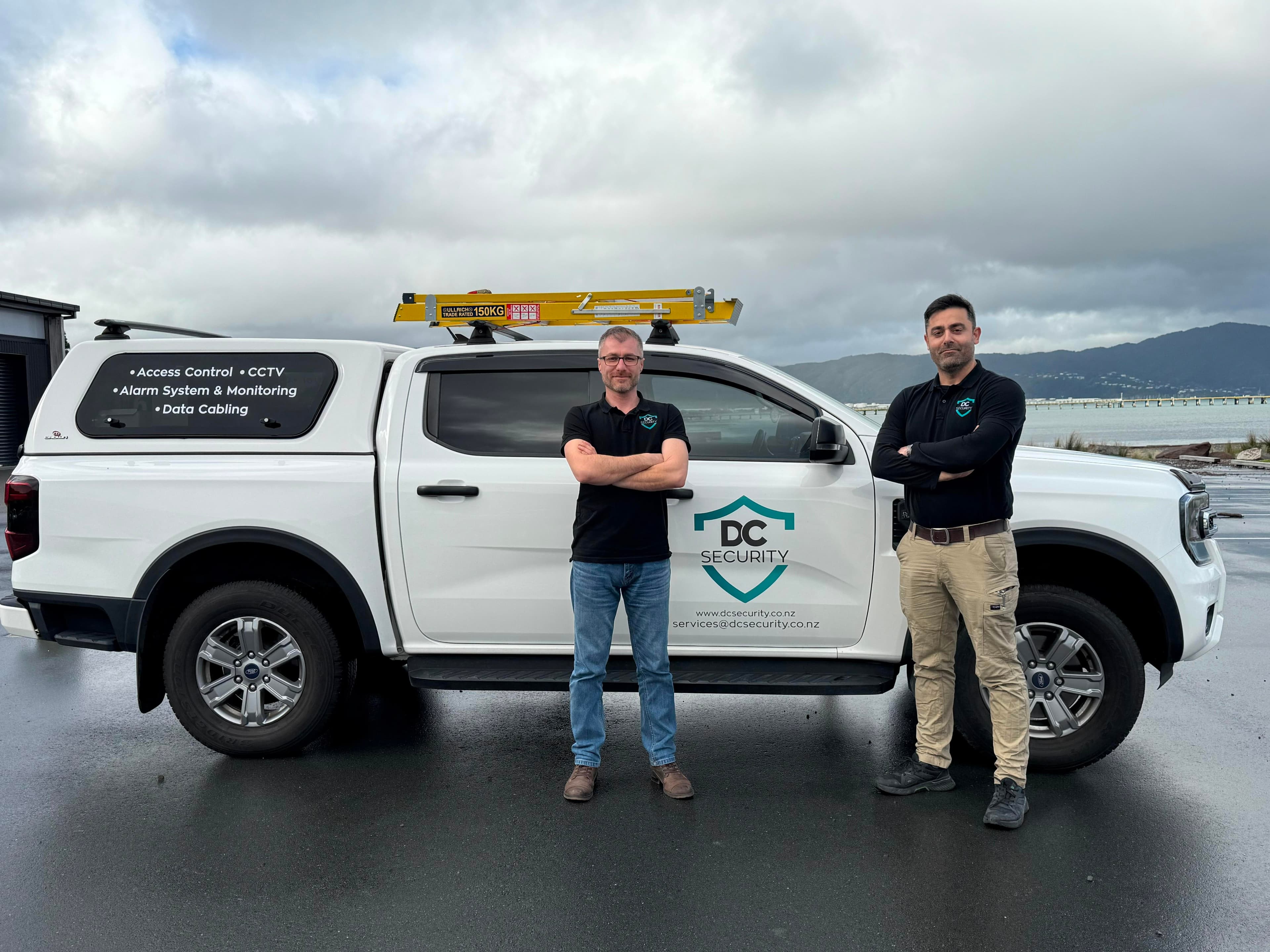 Two DC Security technicians standing in front of a branded service vehicle